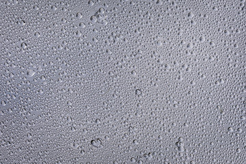 Drops of water after the rain on a glass panel with the sky above