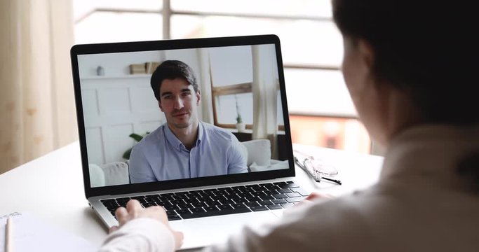 Female hr manager, teacher talking with male job candidate during online webcam interview chat, consulting remote worker or student studying working from home. Over shoulder closeup laptop screen view