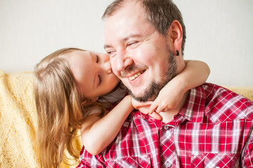 Little girl wishes dad happy father's day. Daughter hugs dad.