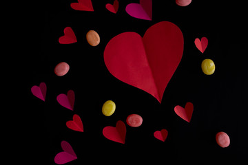 paper heart with sweets on black background
