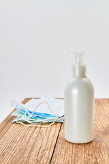 Liquid soap dispenser and blue medical protective masks on wooden background. Hygiene to protection from Covid-19. Coronavirus prevention.