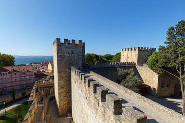 Fototapeta na wymiar Surrounding wall and towers at the historical Sao Jorge Castle (Saint George Castle, Castelo de Sao Jorge) in Lisbon, Portugal, on a sunny day in the summer.