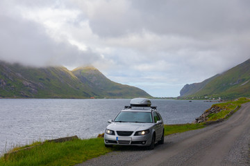 Lofoten, Norway - June 20, 2017: A gray car parked on the shore of a Norwegian fjord