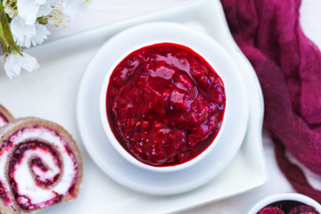Raw raspberry jam in a white cup with raw raspberry rolls. Vegan food.