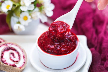 Raw raspberry jam in a white cup and a white spoon. Vegan raw food.