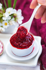 Raw raspberry jam in a white cup and a white spoon. Vegan raw food.