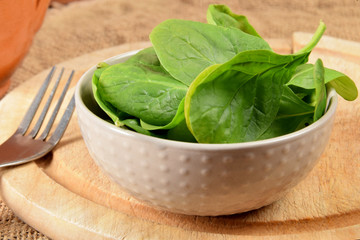 spinach leaves in a bowl on a wooden kitchen board