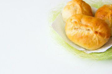 Bakery background. Homemade bakery. Patties on a white and green napkin on white background.Traditional Russian pies (pirozhki). Russian cuisine. Pies with apple, closeup. Sweet dessert.