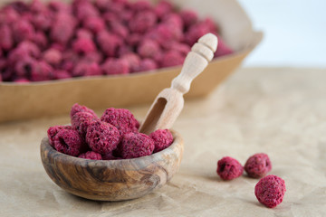Dried raspberries in a wooden bowl on craft paper. Dried berries are a useful product for strengthening immunity.