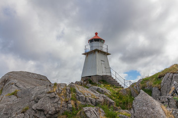 Fototapeta na wymiar Lighthouse in Norwegian fjords, Norway. Sea mountain landscape view.