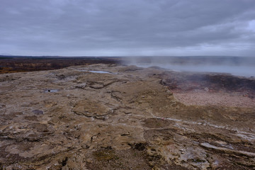 Steam rises from underground vents in and around the Stokkur Geyser in Iceland and the colorful ground runoff