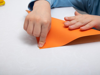 instructions step by step. a child in training at home during quarantine makes origami out of paper. children's creativity. hands close up