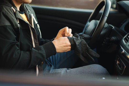 Man in car put on black gloves to protect himself © Aleksandr