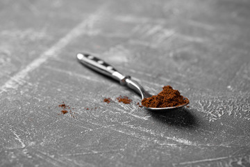 Fragrant ground coffee in a teaspoon steel spoon on a gray background, horizontal format