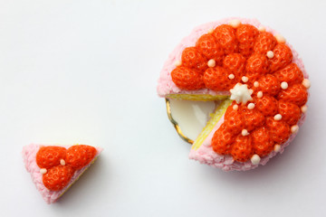 Realistic fake plasticine model of  food.  strawberry cake on a plate and a cut slice next to it made of polymer modeling  clay.