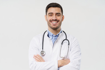 Fototapeta premium Portrait of cheerful lauging young male doctor with stethoscope around neck, wearing white coat, isolated on gray background