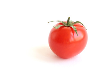 Beautiful small red tomato with green leaves on the top isolated on white background. Cooking Ingredients Theme.