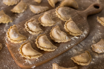 Dumplings with potatoes on board with flour