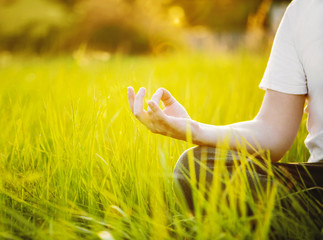 Man is meditating on green grass in the park on sunny summer day. Concept of meditation and healthy lifestyle