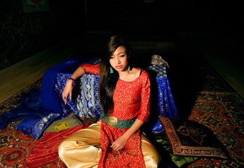 Fototapeta premium young pretty asian girl in bright colored interior on carpet