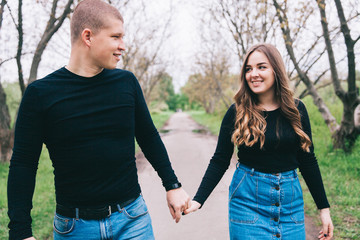 couple in blue jeans and black shirts in a green park