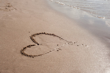 heart drawing on wet sand by the water