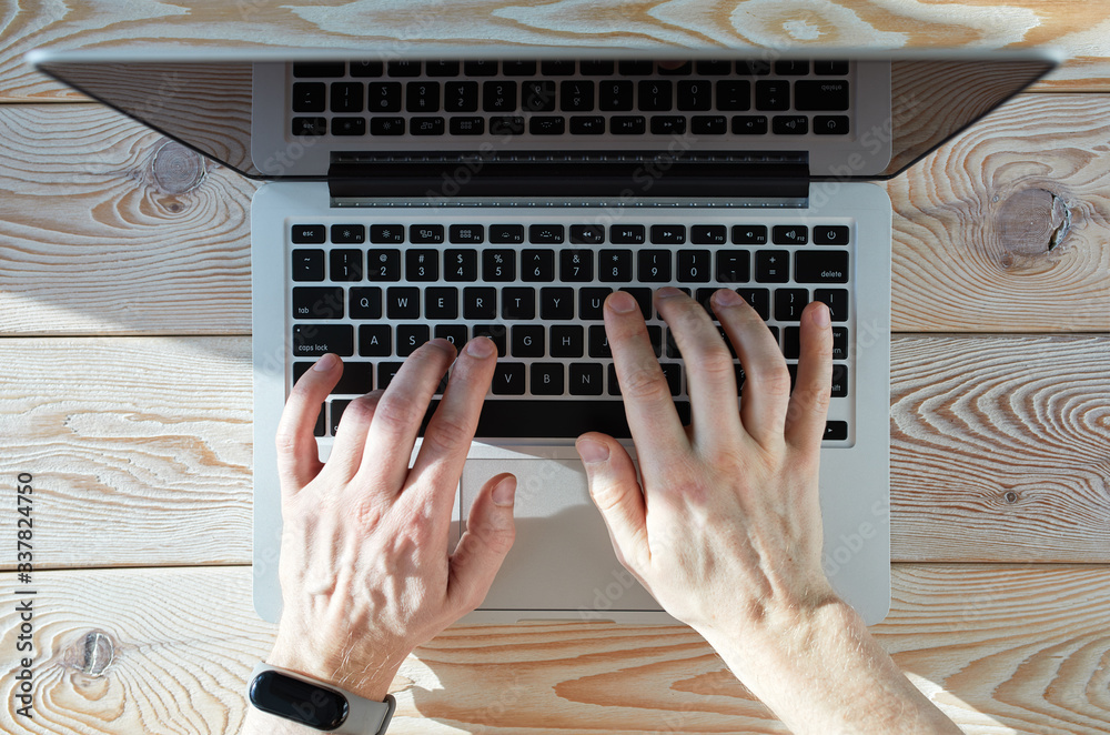Poster top view of man's hands typing on laptop in sunny day. coworking or working at home concept image.