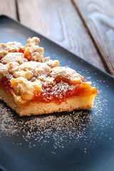 Homemade apricot pie. A slice of rustic hot sweet cake in powdered sugar on the black plate. Natural organic food. Selective soft focus.