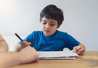 Cropped shot father and Son doing homework together, Child boy learning math at home during covid lock down,Home schooling and concept of COVID-19 pandemic infection.