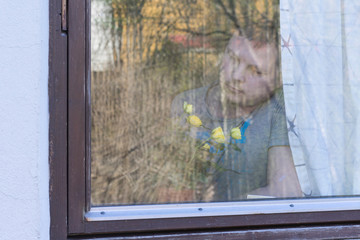 A man near the window smelling blooming rose.