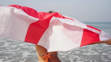 Young woman in a swimsuit with an English flag on the beach - Powered by Adobe