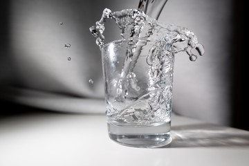 
water in a transparent glass with splashes on a blurred background