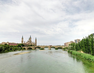 View of the Cathedral-Basilica of Our Lady of the Pillar, a Roman Catholic church on river Ebro and the Old Stone bridge in the city of Zaragoza, in Aragon, Spain.