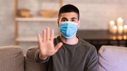 Man wearing surgical mask showing stop hand gesture