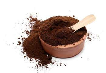 Pile of powdered, instant coffee for espresso with wooden spoon and clay pot isolated on white background