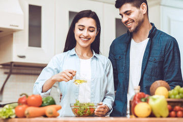 Happy young couple preparing salad together at home