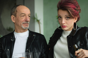 Close-up portrait of a couple with age difference drinking an alcohol in loft style room, alcoholism problems in the family
