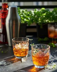 orange summer cocktail with ice on dark background. Shadows of glasses, hard sun light.