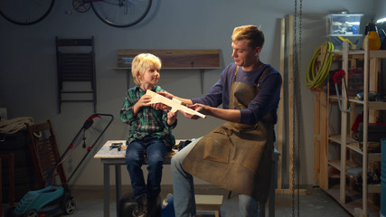 Father repairs the toy of his son. Medium long shot
