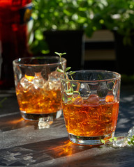 orange summer cocktail with ice on dark background. Shadows of glasses, hard sun light.