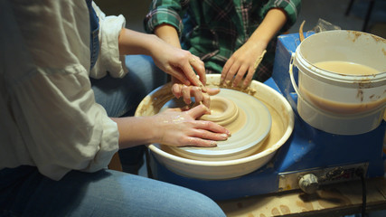 Mom and child together make a vase on a pottery wheel