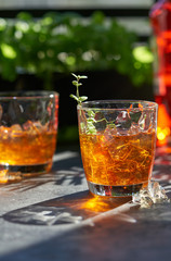 orange summer cocktail with ice on dark background. Shadows of glasses, hard sun light.