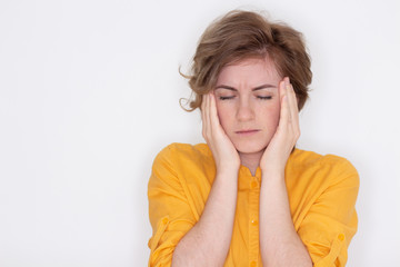 An unhappy, exhausted girl with closed eyes, touches her temples in close-up, a tired woman suffers from a headache or migraine, does not feel well, suffers from insomnia, lack of sleep