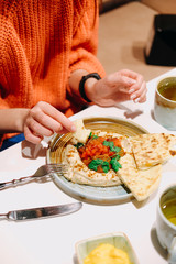a woman eats hummus with a flatbread - 337838363