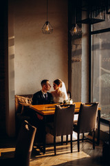 The groom hugs the bride and they look each other. Beautiful elegant couple of newlyweds in love in a loft interior. Wedding concept. Happy newlywed couple.