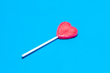 Red lollipop heart isolated on blue background