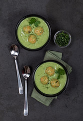Soup-puree of greens with meatballs in a bowl on a dark background top view
