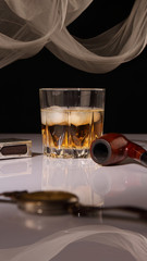 A glass of whiskey, a pipe, and a watch