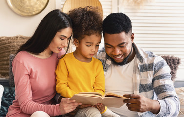 International family reading book together at home