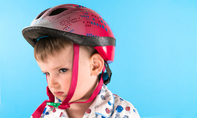 Boy in a protective helmet on a blue background. Safety, child.
